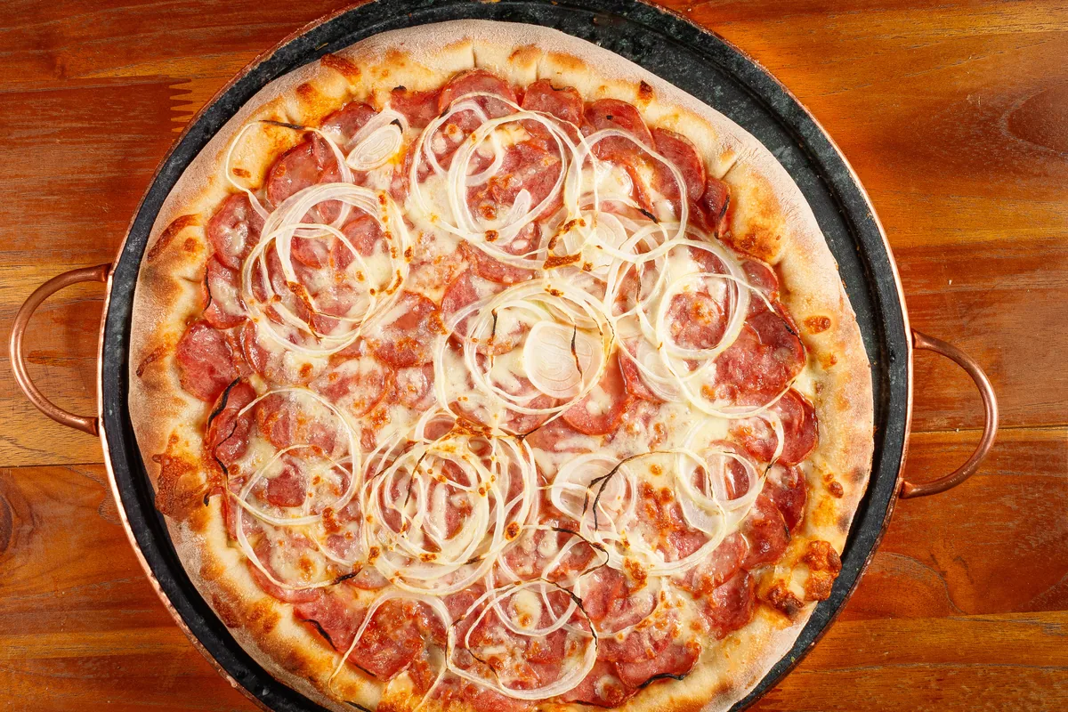Pizza inteira vista de cima sobre mesa de madeira