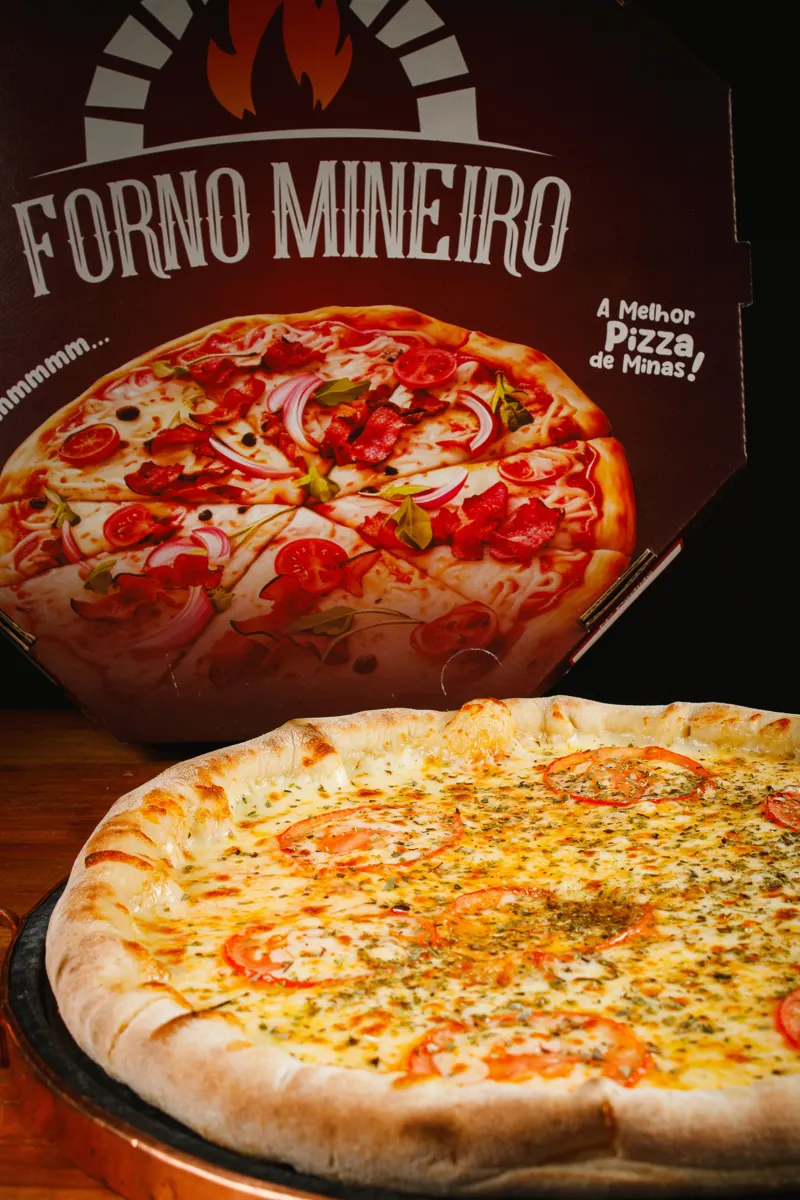 Pizza inteira ao lado da caixa do Forno Mineiro